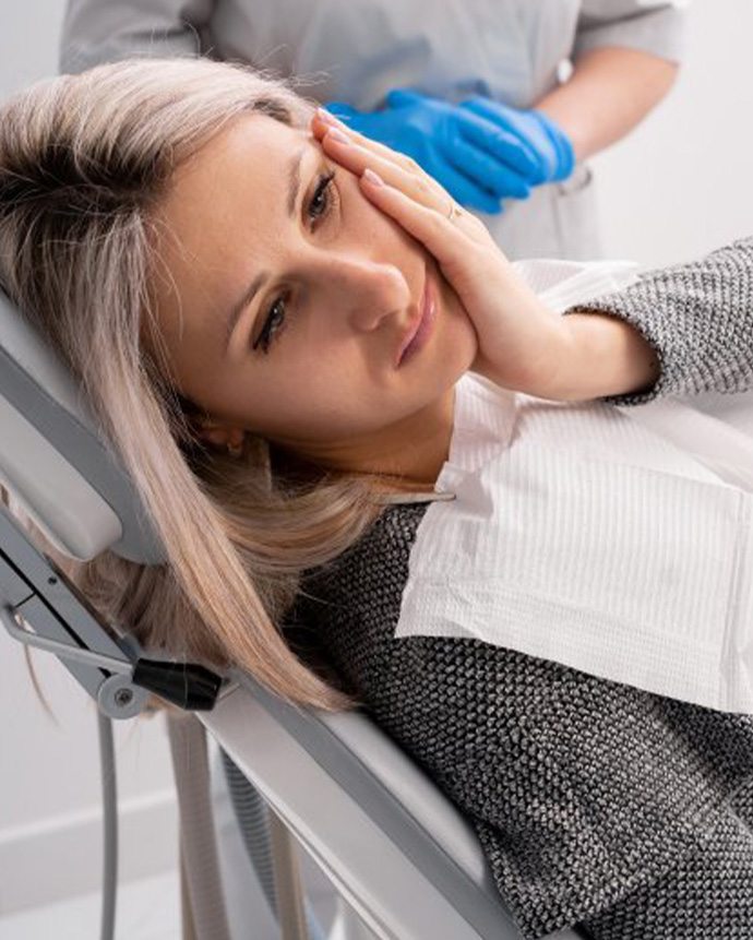 Woman talking to dentist holding jaw in pain