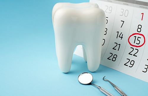 Large model tooth next to a calendar with the 15th circled in red to indicate appointment