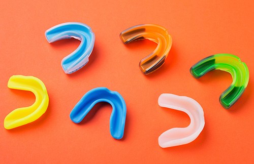 Several colorful mouthguards on an orange background