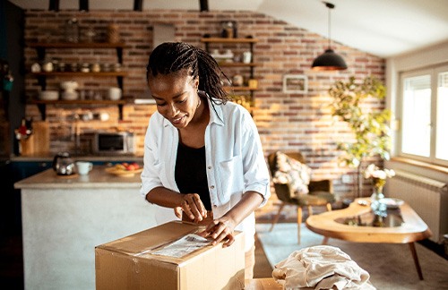 Woman opening a box at a table by her kitchen