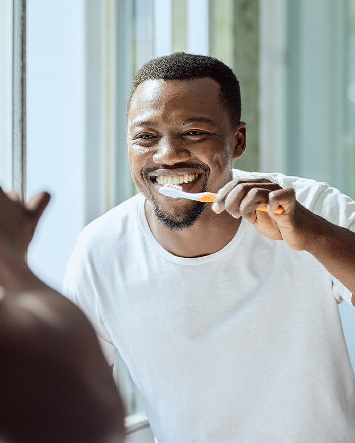 a smiling man brushing his teeth