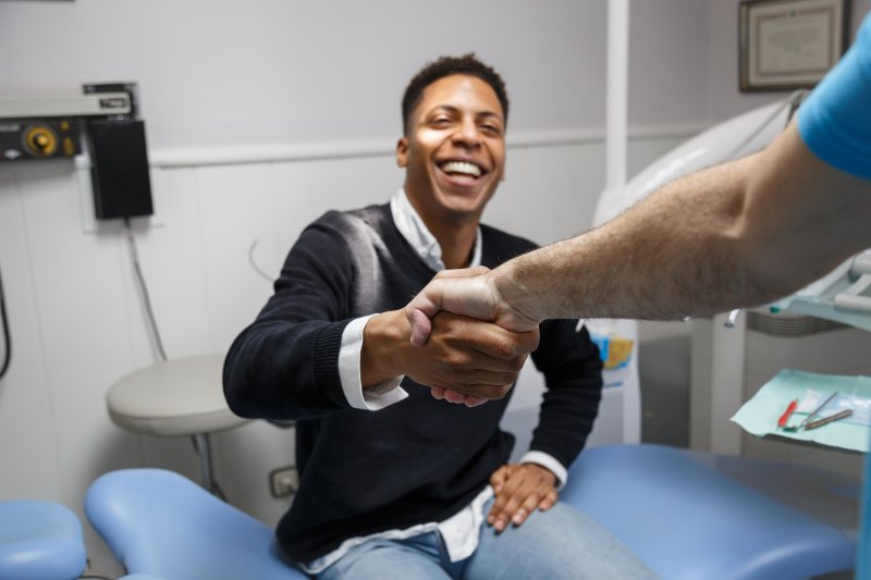Patient shaking hands with dentist at consultation for dental implants