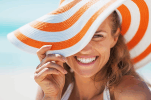 Woman in a giant sunhat smiling at the beach