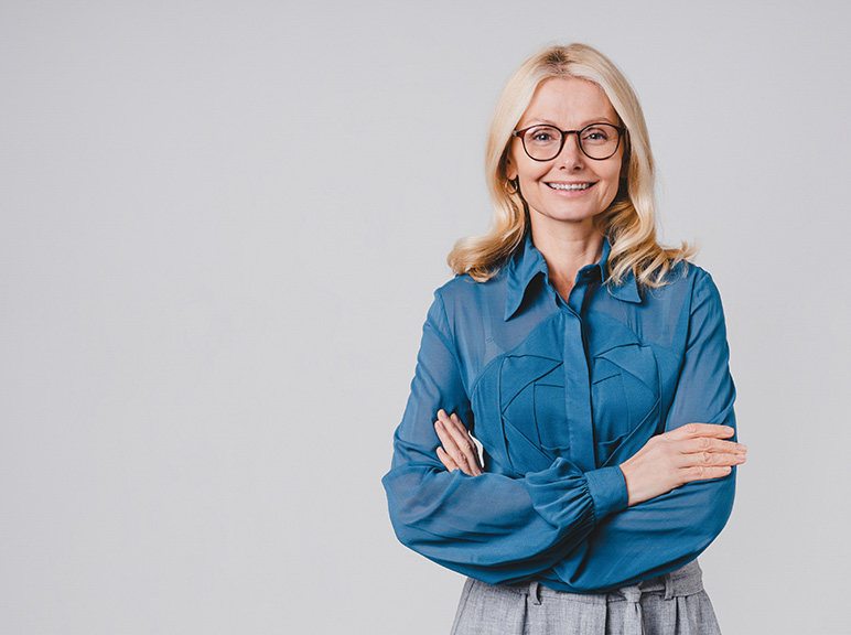 Professional woman with glasses smiling confidently against a plain background.
