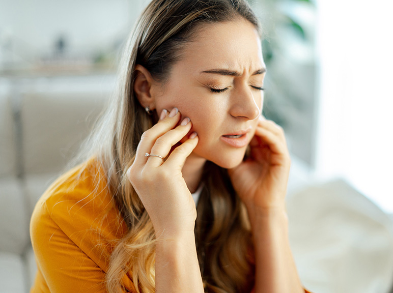 Woman holding her jaw in pain, suggesting toothache or jaw discomfort.