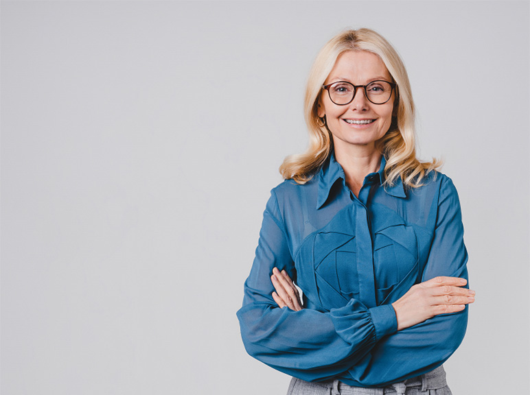 Professional woman with glasses smiling confidently against a plain background.